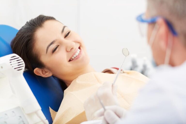 A woman receives a Wisdom dental cleaning as she brushes her teeth with a toothbrush, promoting oral hygiene.