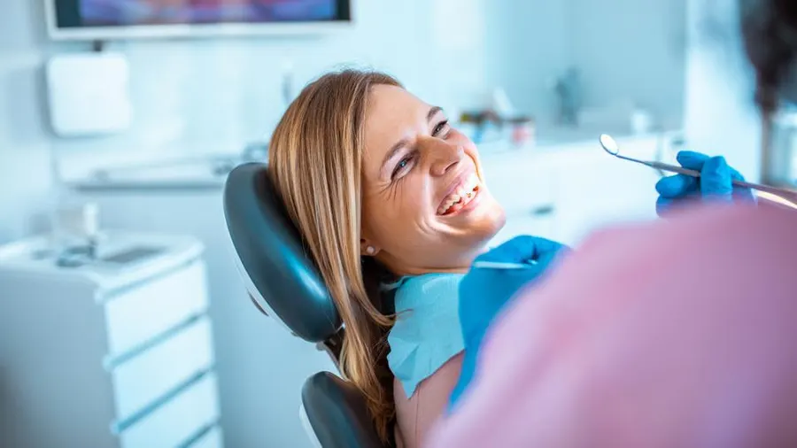 A smiling couple observes as a dentist examines the woman's teeth, highlighting a friendly dental environment.