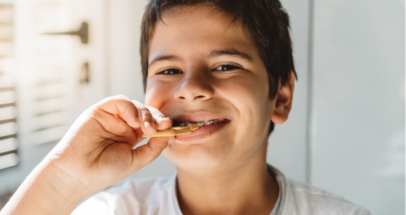 A smiling boy holds a cookie, radiating joy and delight in a cheerful moment.