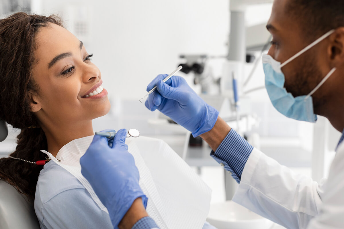 A smiling couple observes as a dentist examines the woman's teeth, highlighting a friendly dental environment.