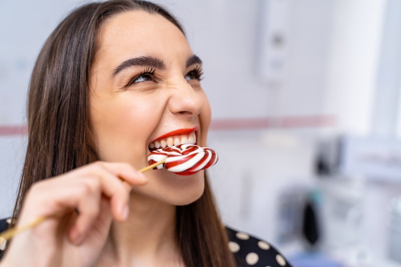 A woman enjoying a colorful candy lollipop with a joyful expression on her face.